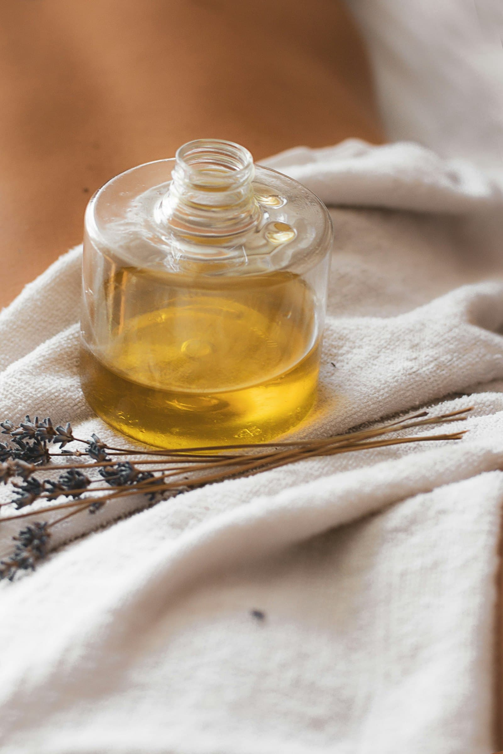 A treatment-oil jar with lavender resting on linen